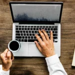 Person typing on a laptop at a wooden desk while reading a blog such as pushwiki com